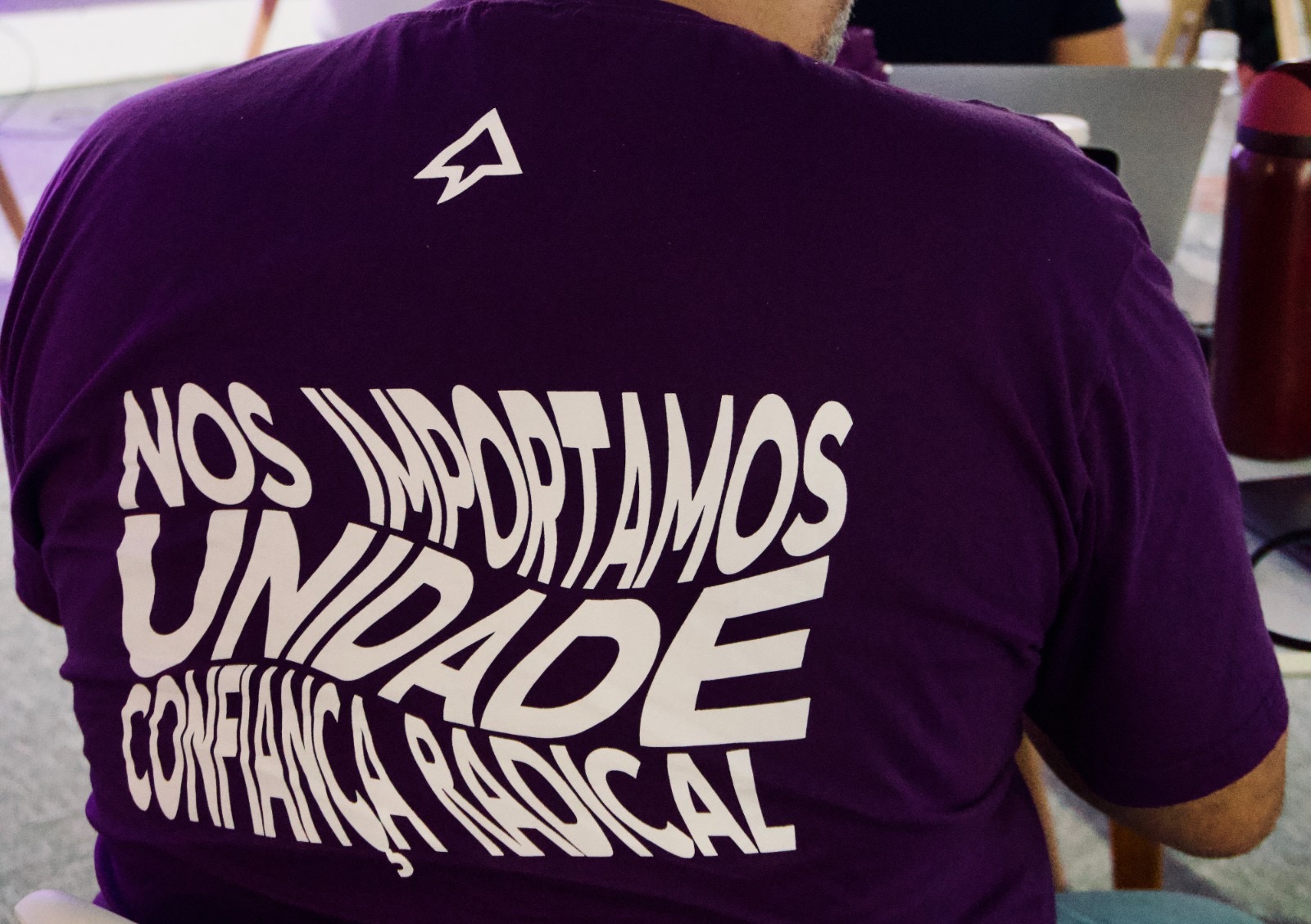 Costas da camiseta do offsite com os valores Nos importamos, Unidade e Confiança radical